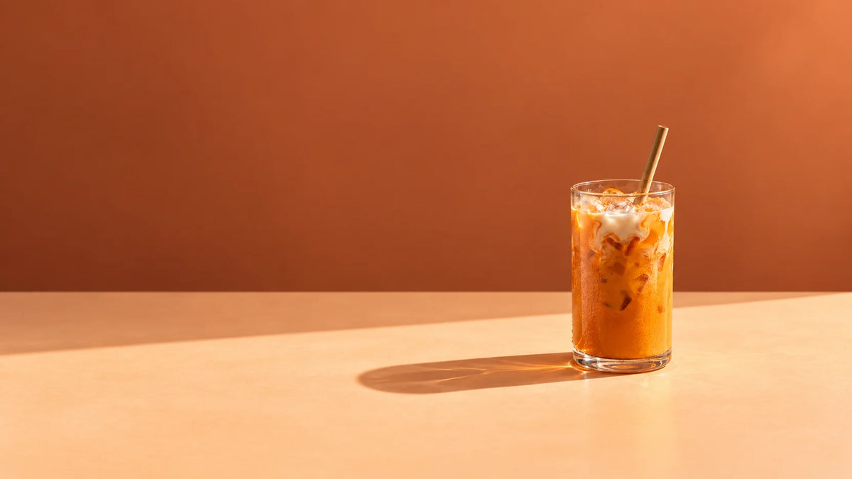 A glass of Thai iced tea on a sunlit home kitchen counter